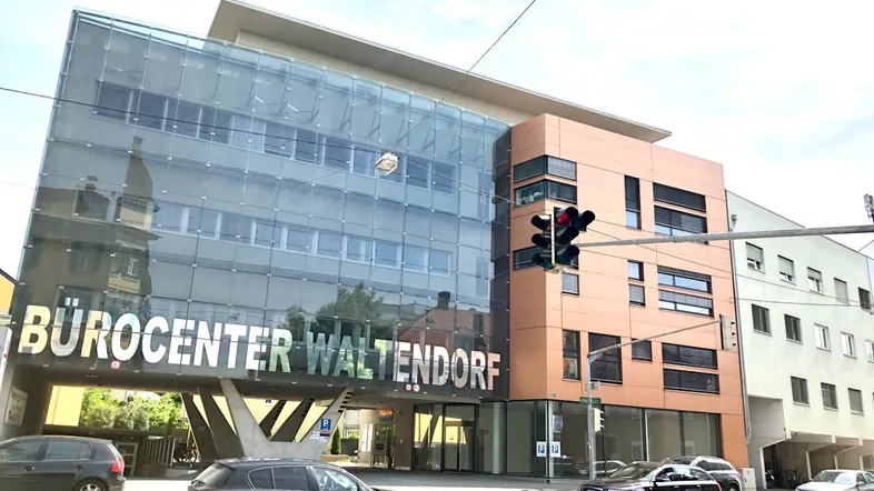 Modernes Bürogebäude mit Glasfassade und markanter Architektur in städtischer Umgebung.
