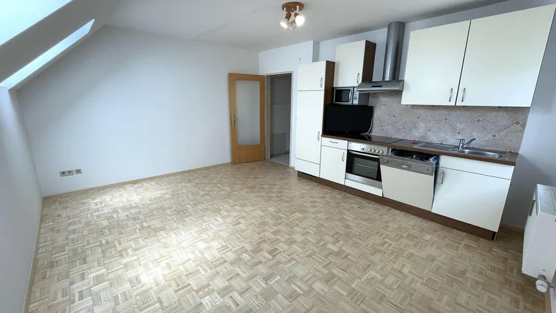 Heller Wohnbereich mit integrierter Küchenzeile, Parkettboden und Dachfenster.