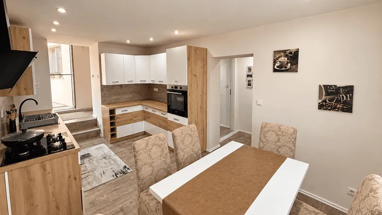 Moderne Küche mit Holz- und weißen Fronten, integrierten Geräten und Essbereich.