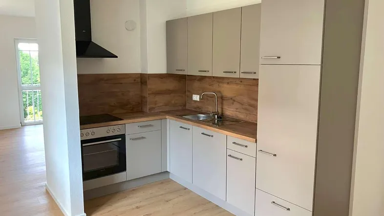 Moderne Einbauküche in Grau mit Holzoptik-Arbeitsplatte und integrierten Geräten.