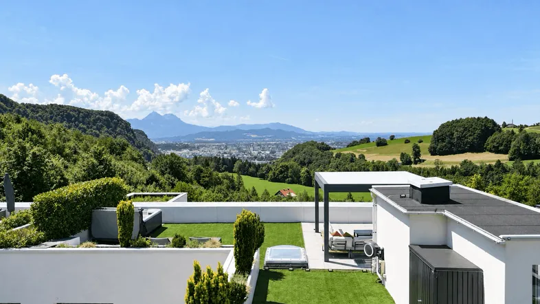 Weitläufige Dachterrasse mit Kunstrasen, Whirlpool und atemberaubendem Blick auf die Stadt und Berge.