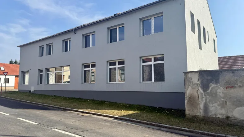 Modernes Gebäude mit heller Fassade und vielen Fenstern an einer Straße gelegen.