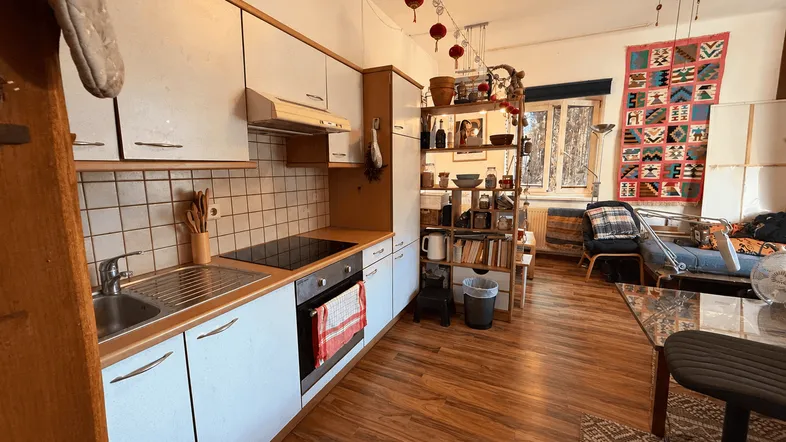 Offener Wohnbereich mit integrierter Küche, Holzboden und farbenfroher Dekoration.