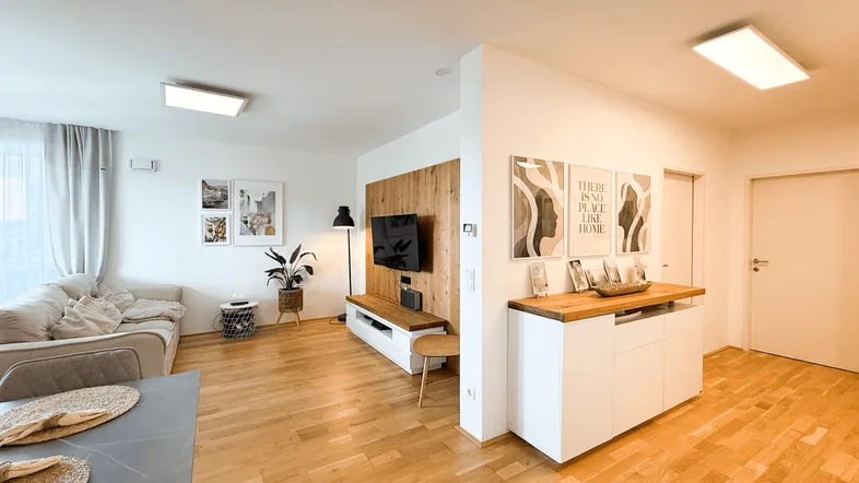 Helles Wohnzimmer mit Holzboden, modernem TV-Möbel und stilvoller Dekoration.