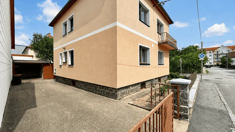 Hausfassade in hellem Ocker mit Einfahrt und Garage, umgeben von einer ruhigen Wohngegend.