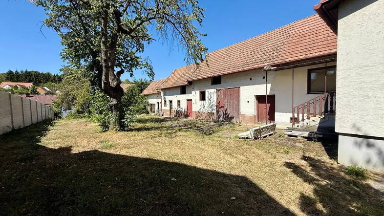Ländliches Anwesen mit mehreren Gebäuden und großem Grundstück unter blauem Himmel.