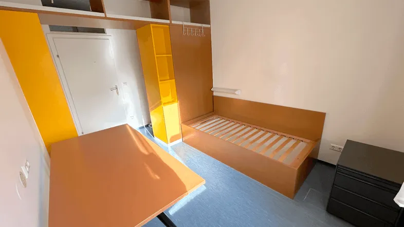Helles Schlafzimmer mit Schreibtisch, Bettrahmen und gelben Regalen für Stauraum.