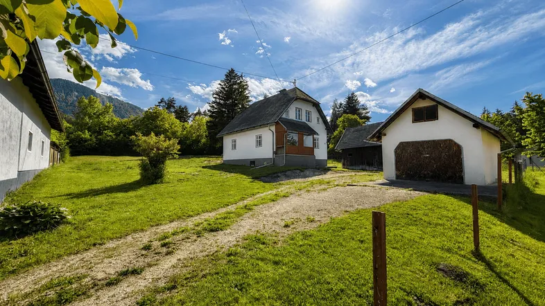 Ländliches Anwesen mit Einfamilienhaus, Nebengebäude und großem Garten unter blauem Himmel.