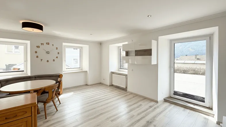 Helles Wohn- und Esszimmer mit Holzboden, gemütlicher Sitzecke und Zugang zur Terrasse.