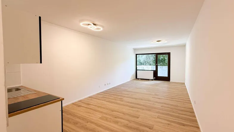 Heller Wohnbereich mit neuem Laminatboden und Zugang zu einem Balkon oder einer Terrasse.