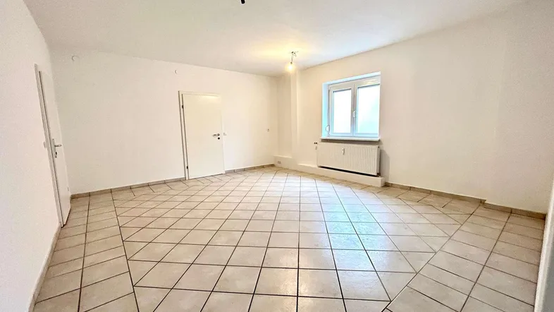 Heller, leerer Raum mit Fliesenboden und Fenster, bereit zur individuellen Gestaltung.