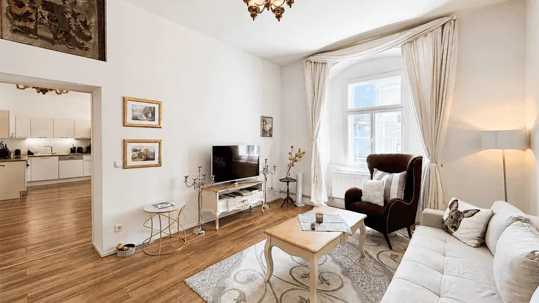Helles Wohnzimmer mit Holzboden, bequemen Sofas und offenem Übergang zur Küche.
