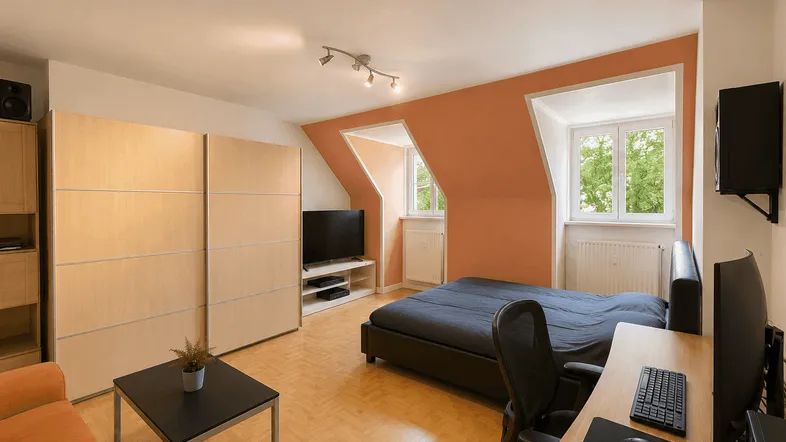 Helles Schlafzimmer mit Dachschrägen, integriertem Arbeitsbereich und großem Kleiderschrank.