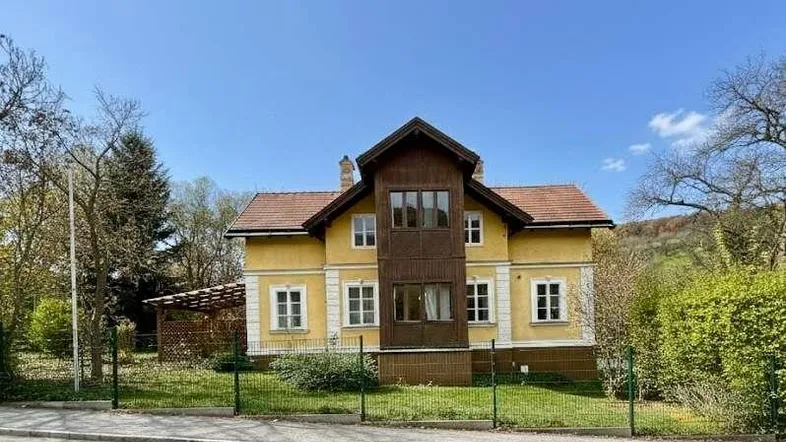 Gut erhaltenes gelbes Einfamilienhaus mit Holzanbau und großem Garten.