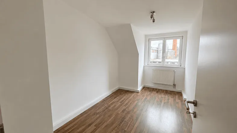 Helles Zimmer mit Dachschräge und Laminatboden, ideal als Schlaf- oder Arbeitszimmer.