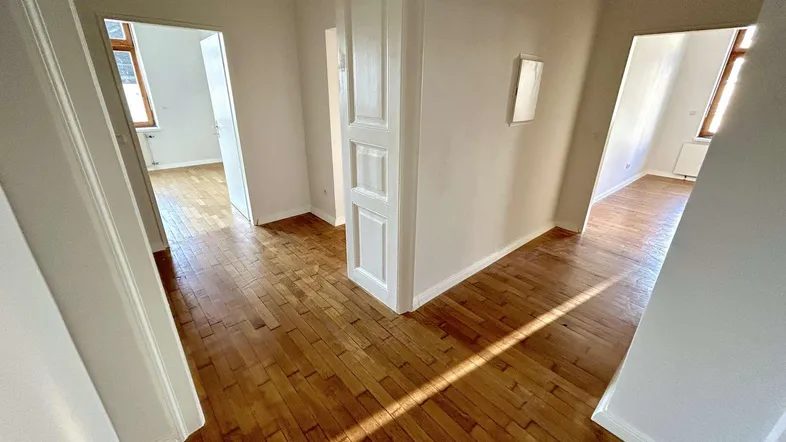 Heller Flur mit Holzboden und Zugang zu mehreren Zimmern, gut beleuchtet durch natürliches Licht.