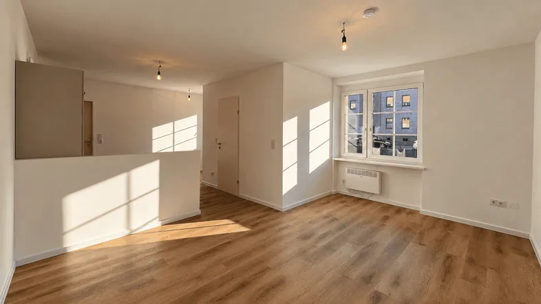 Helles Wohnzimmer mit Laminatboden und viel Tageslicht durch das Fenster.