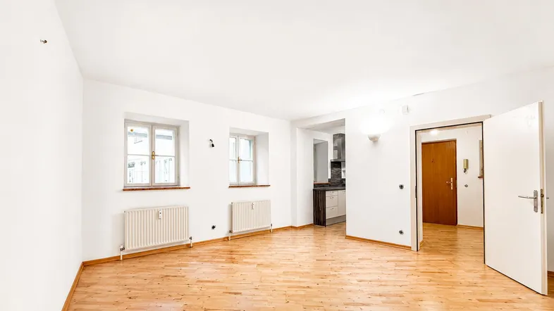 Helles Zimmer mit Holzboden und zwei Fenstern, bereit zur individuellen Gestaltung.