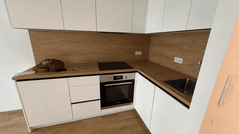 Moderne Einbauküche mit weißen Schränken, Holzoptik-Arbeitsplatten und integrierten Geräten.