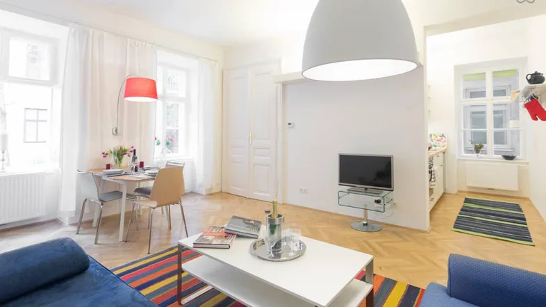 Helles Wohn- und Esszimmer mit Parkettboden, farbenfrohem Teppich und moderner Einrichtung.