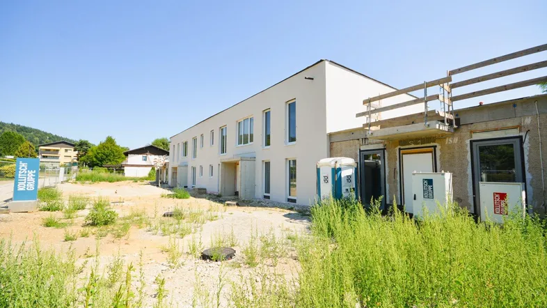 Neubauprojekt mit moderner Architektur und Baustellenbereich unter blauem Himmel.