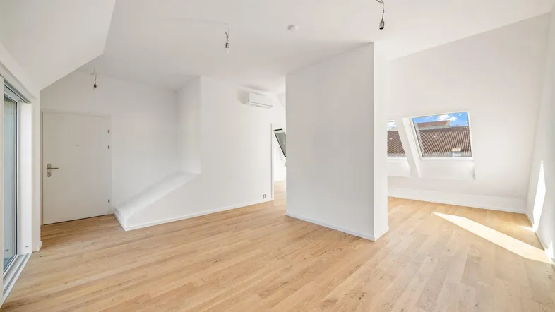 Helles Dachgeschosszimmer mit Holzboden, schrägen Wänden und Dachfenstern, bereit zur individuellen Gestaltung.