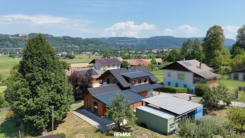 Luftaufnahme des Hauses mit umliegender Landschaft und Bergen im Hintergrund.