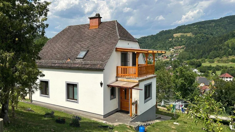 Freistehendes Einfamilienhaus mit Balkon und Garten in ländlicher Umgebung mit Bergblick.