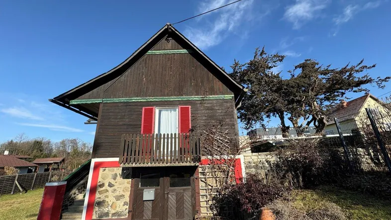 Traditionelles Holzhaus mit Steinsockel, kleinem Balkon und Satteldach.