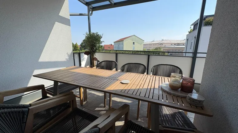 Sonniger Balkon mit Glasüberdachung und Esstisch, ideal für Mahlzeiten im Freien.