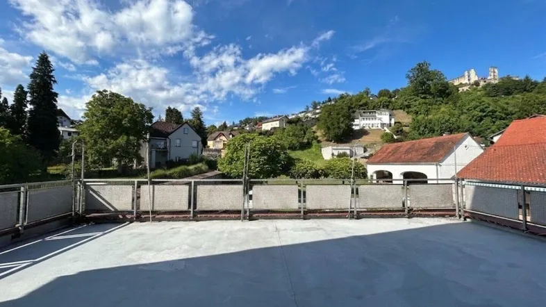 Große Dachterrasse mit weitem Blick auf die umliegende Landschaft und eine historische Burgruine.