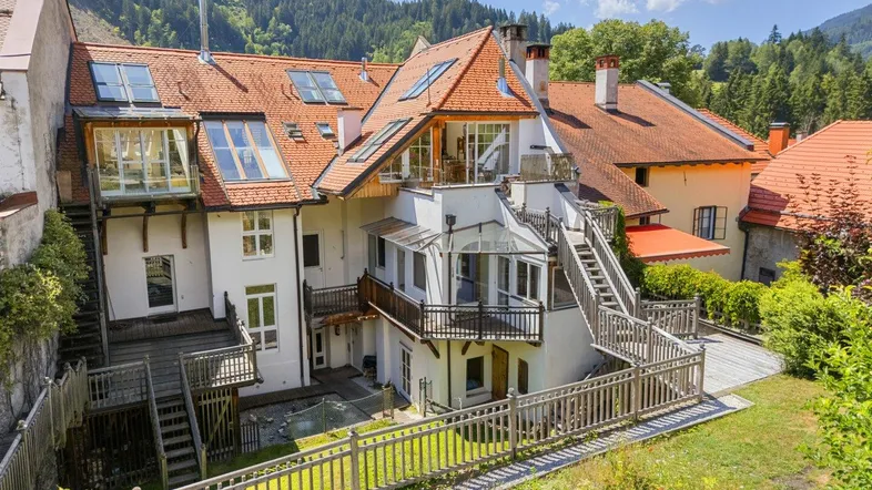 Großzügiger Gartenbereich mit Holzterrassen, Treppen und Blick auf die umliegende Berglandschaft.