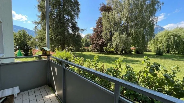Heller Balkon mit Fliesenboden und weitem Blick ins Grüne und auf die Berge.