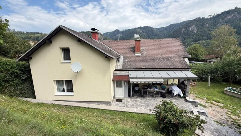 Ansicht des Hauses von oben mit überdachter Terrasse und Blick auf die umliegende Berglandschaft.