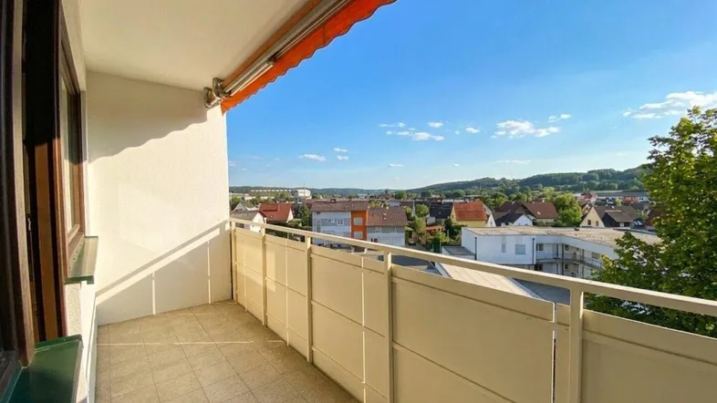 Heller Balkon mit Markise und weitem Blick über die Stadt und die umliegende Landschaft.