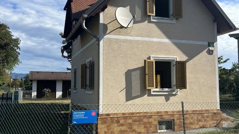 Ansicht des Hauses von der Seite mit Fenstern, Fensterläden und einem kleinen Vorgarten.
