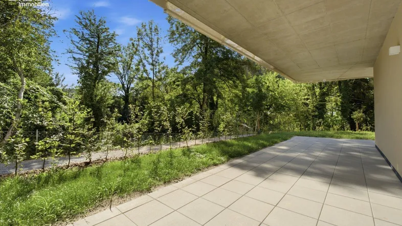 Grosse gepflasterte Terrasse mit Überdachung und Blick ins Grüne, ideal für Entspannung im Freien.