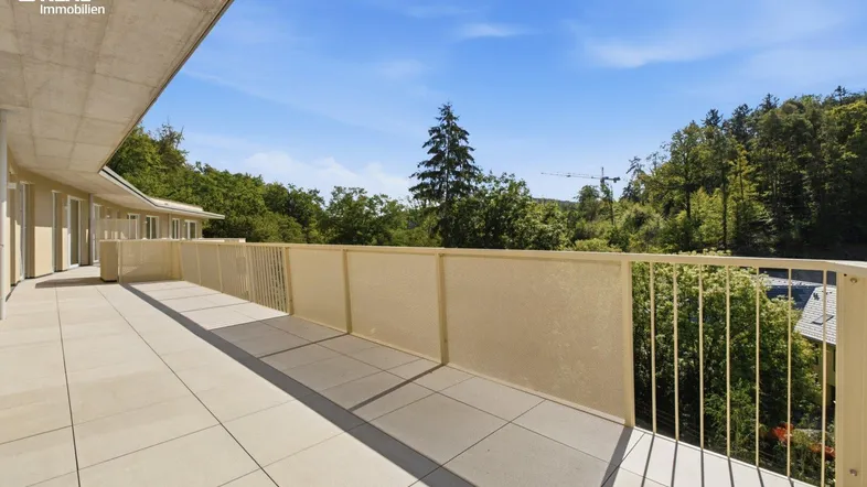 Große, geflieste Terrasse mit weitem Blick ins Grüne und moderner Brüstung.
