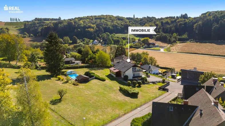 Luftaufnahme eines Hauses mit Pool und grüner Umgebung in ländlicher Lage.
