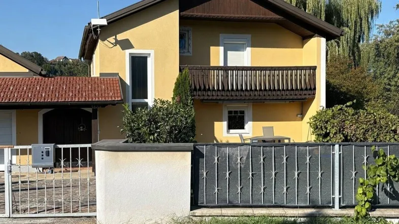 Gelbes Einfamilienhaus mit Balkon und Vorgarten in sonniger Lage.