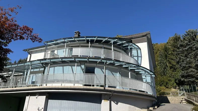 Modernes Wohnhaus mit runden Balkonen und integrierter Garage unter blauem Himmel.
