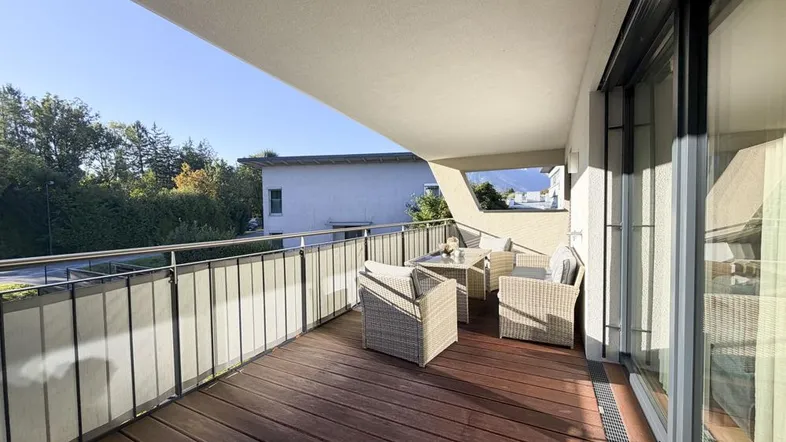 Geräumiger Balkon mit Holzboden und bequemen Outdoor-Möbeln, ideal für entspannte Stunden im Freien.