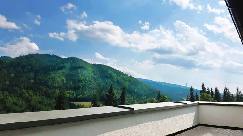 Geräumige Terrasse mit Fliesenboden und weitem Blick auf die grüne Berglandschaft.