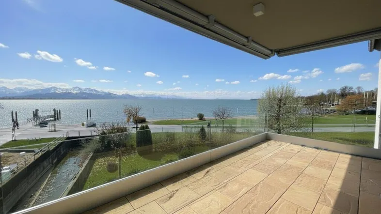 Geräumige Terrasse mit Fliesenboden und atemberaubendem Blick auf den See und die Berge.