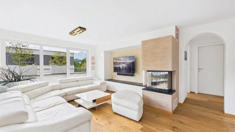 Helles Wohnzimmer mit modernem Kamin, großem Sofa und Zugang zu einer Terrasse.