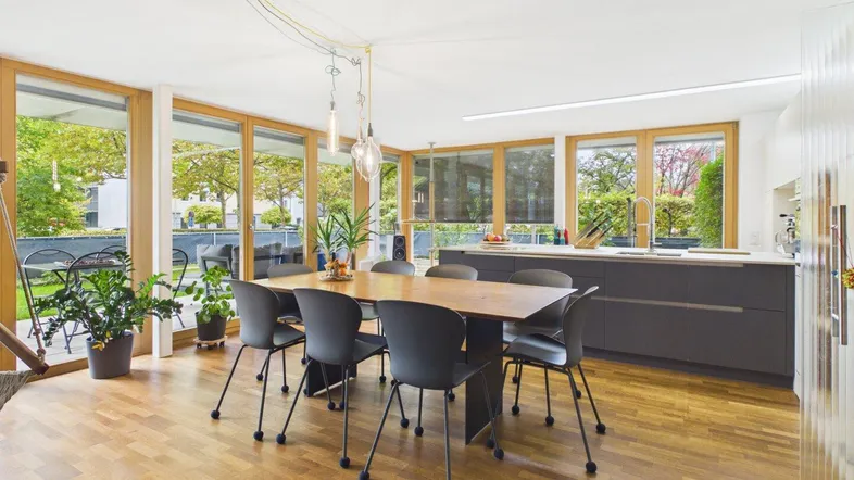 Heller offener Wohn- und Essbereich mit moderner Küche, Holzboden und Zugang zur Terrasse.