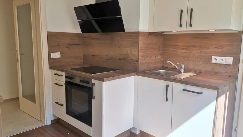 Moderne Einbauküche mit weißen Fronten, Holzoptik-Arbeitsplatten und integrierten Geräten.