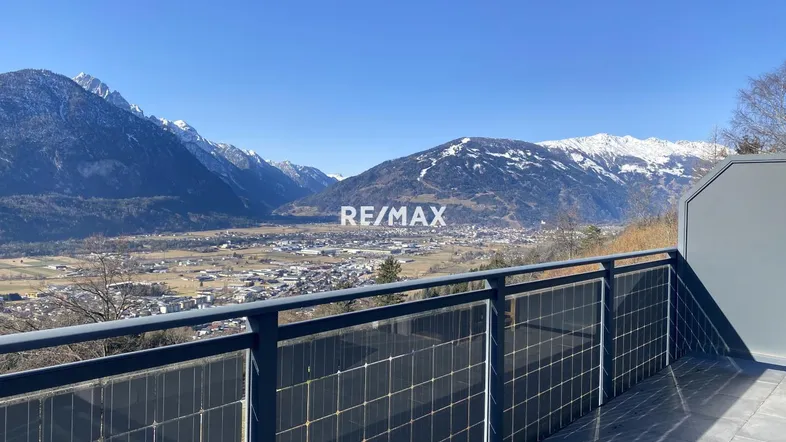 Geräumige Terrasse mit Panoramablick auf die Berge und das Tal, ausgestattet mit Solarmodulen am Geländer.