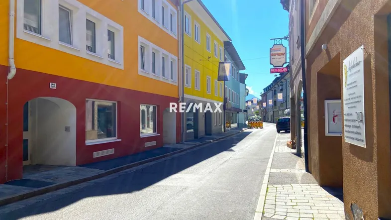 Bunte Gebäude entlang einer sonnigen Straße in einer historischen Stadtansicht.