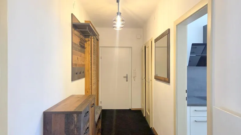 Heller Flur mit Holzoptikboden, Garderobe und Zugang zur Küche.